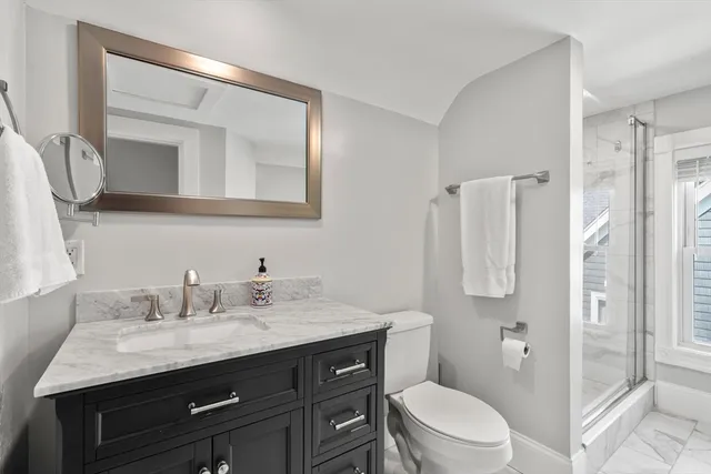 a bathroom with a granite countertop toilet sink and mirror