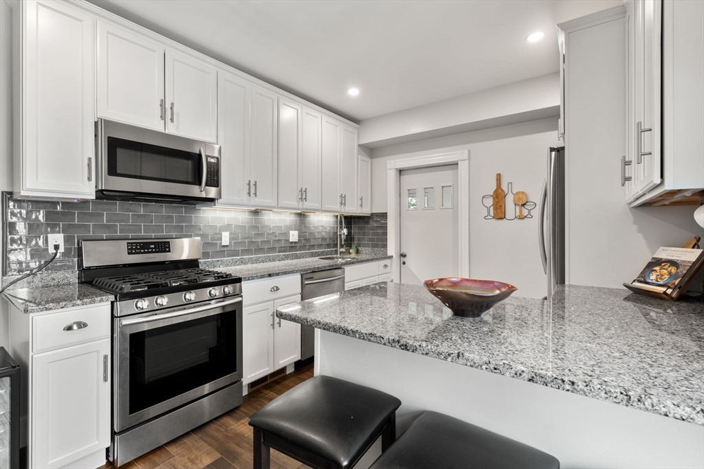103 Belgrade Avenue, Unit 2 Boston, MA 02131 - Photo 2 of 24 a kitchen with stainless steel appliances granite countertop a stove a sink and a microwave