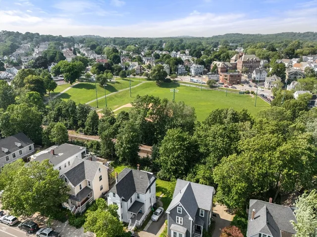 an aerial view of residential houses with outdoor space and trees