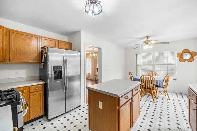 a kitchen with stainless steel appliances a refrigerator a sink a stove a dining table and chairs with wooden floor