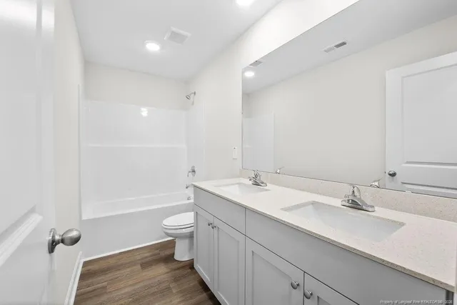 a bathroom with a double vanity sink toilet mirror and bathtub