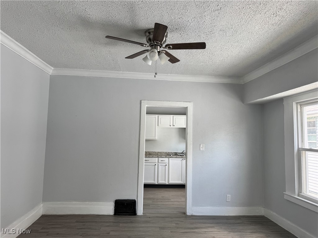 3624 East 118th Street Cleveland, OH 44105 - Photo 32 of 49 Spare room with a textured ceiling, a ceiling fan, ornamental molding, and dark wood-style floors