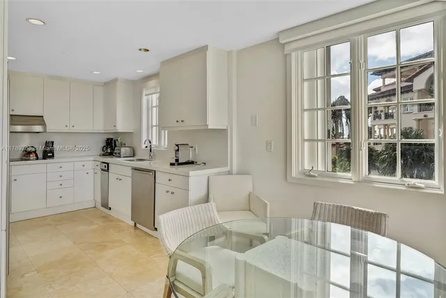 a kitchen that has a lot of white cabinets and stainless steel appliances