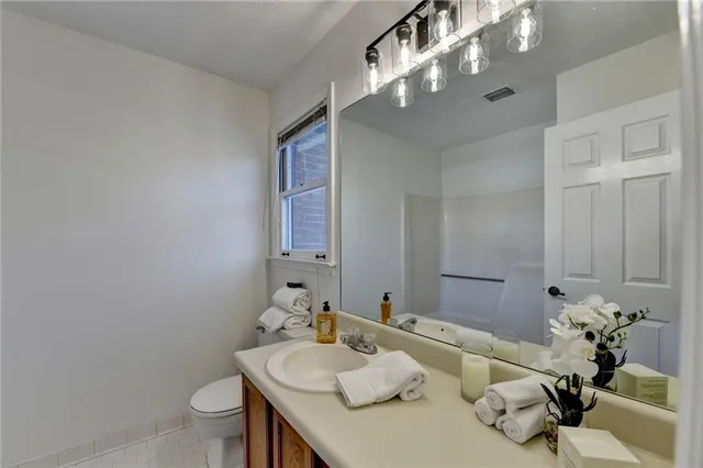 a bathroom with a granite countertop sink a toilet and a mirror
