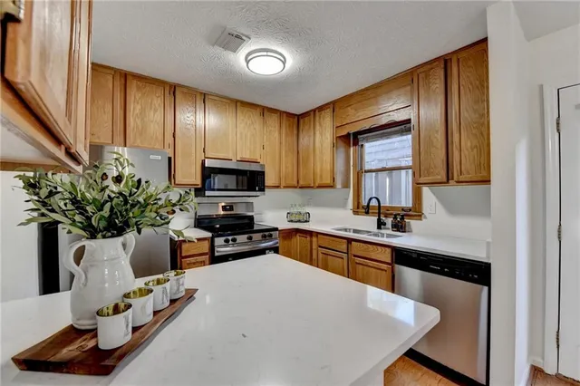 a kitchen with granite countertop a sink stainless steel appliances and cabinets