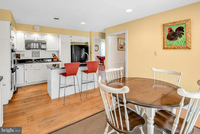 a kitchen with stainless steel appliances granite countertop a dining table chairs and a refrigerator