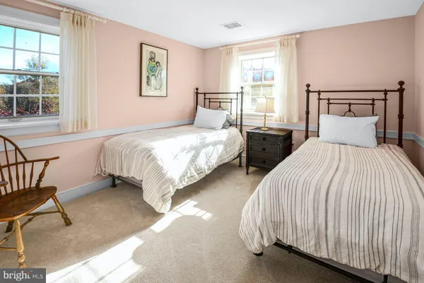 a bedroom with two beds and next to a window