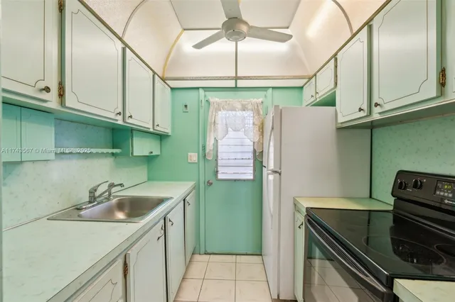 a kitchen with a sink a refrigerator and cabinets
