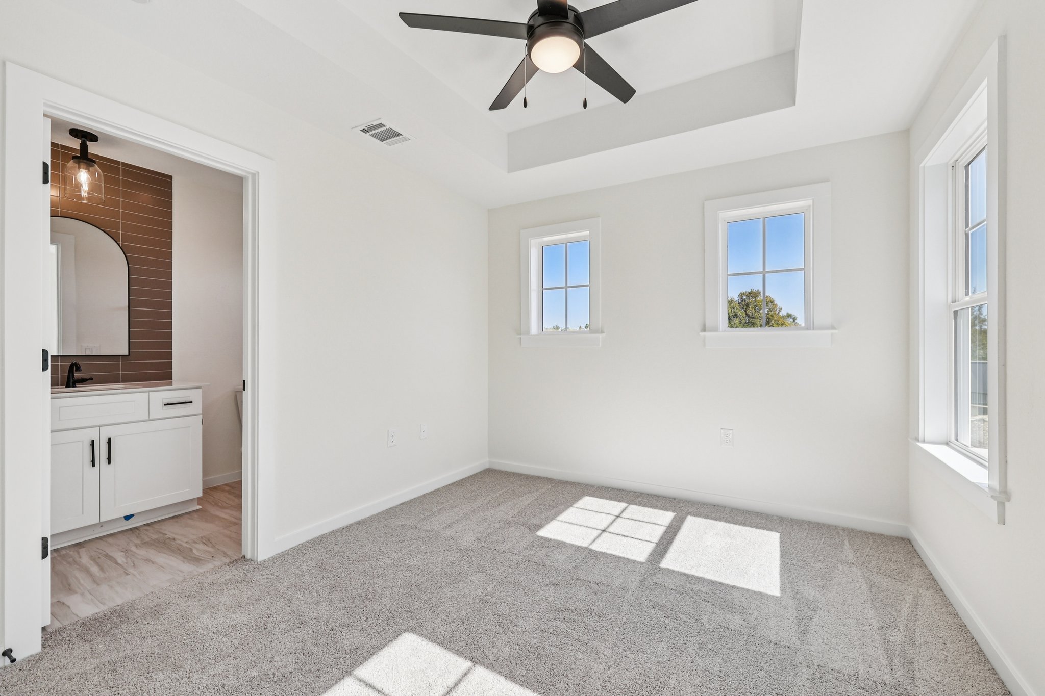 2414 Drew Lane, Unit 3 Austin, TX 78748 - Photo 11 of 18 Unfurnished bedroom with light carpet, a ceiling fan, a raised ceiling, and ensuite bath
