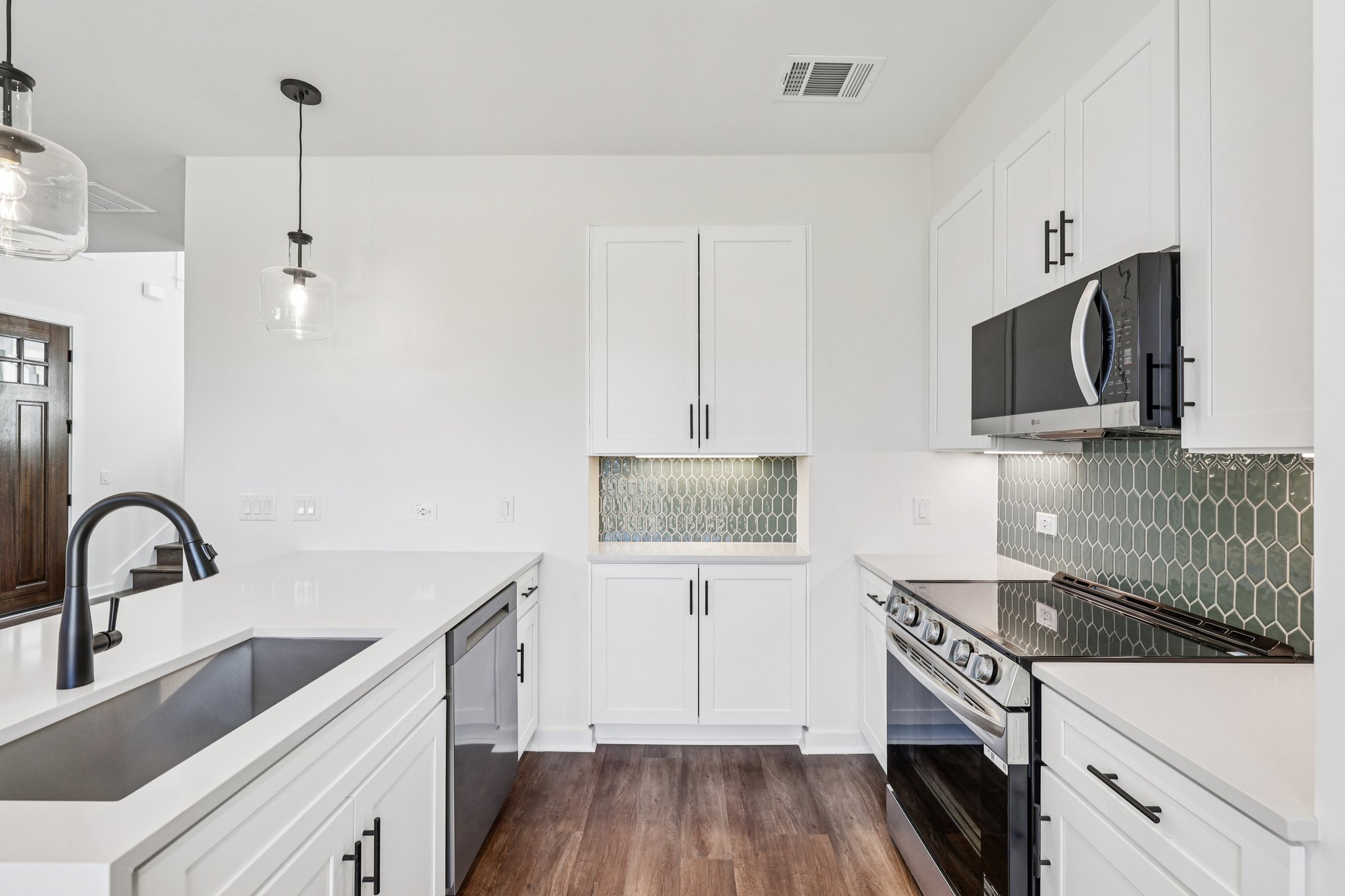 2414 Drew Lane, Unit 3 Austin, TX 78748 - Photo 8 of 18 Kitchen with stainless steel appliances, backsplash, white cabinetry, hanging light fixtures, and dark wood finished floors