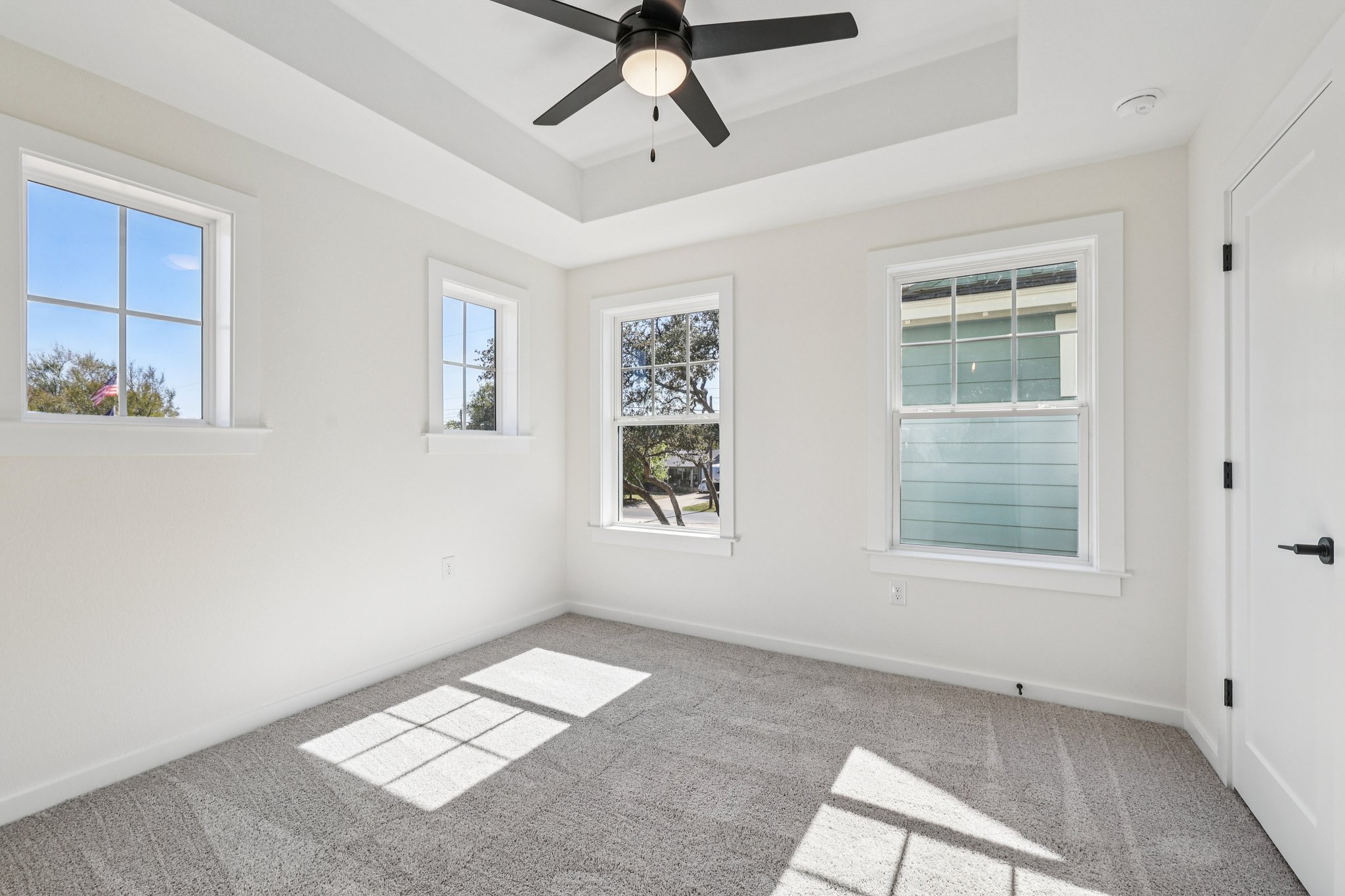 2414 Drew Lane, Unit 3 Austin, TX 78748 - Photo 10 of 18 Empty room with healthy amount of natural light, ceiling fan, light colored carpet, and a tray ceiling