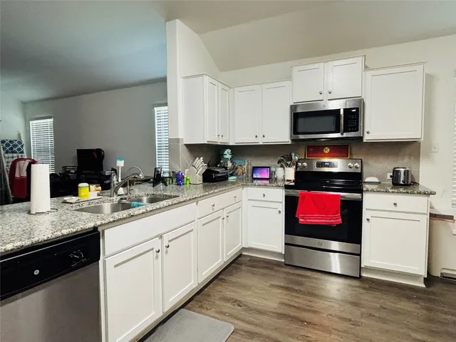 a kitchen with stainless steel appliances granite countertop a sink dishwasher stove top oven and cabinets with wooden floor