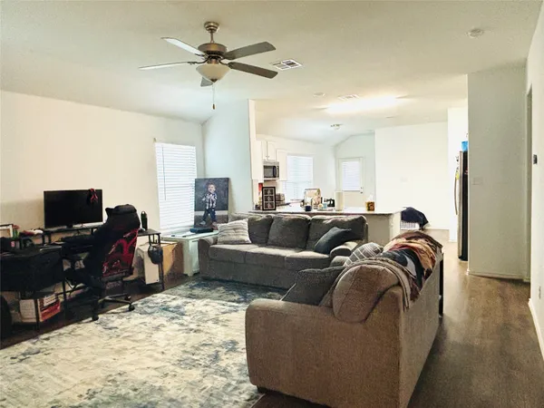 a living room with furniture a flat screen tv and a ceiling fan
