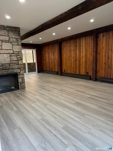 an empty room with wooden floor fireplace and windows