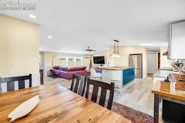 a living room with chairs kitchen view and a wooden floor