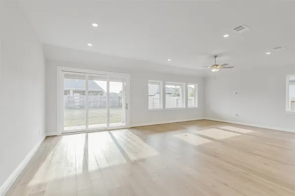 a large kitchen with stainless steel appliances granite countertop a stove top oven a sink a refrigerator and white cabinets with wooden floor