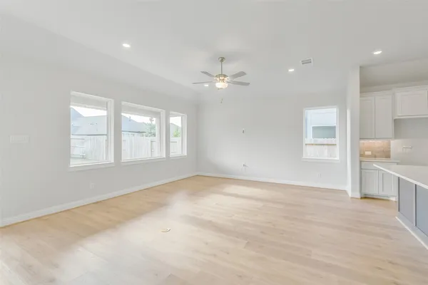 a view of kitchen with granite countertop refrigerator oven a sink and white cabinets with wooden floor