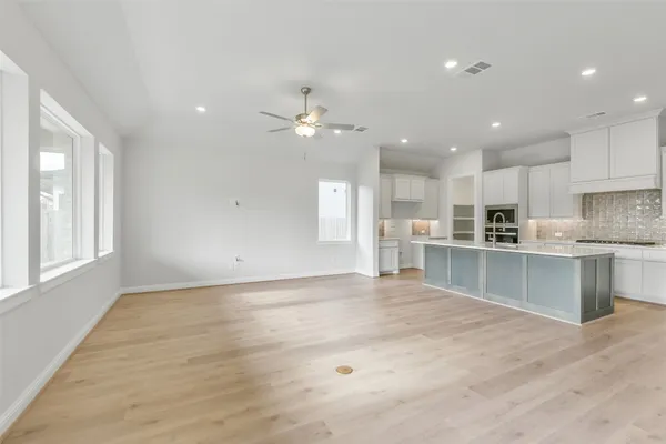 a large kitchen with stainless steel appliances kitchen island a large counter top and wooden floors