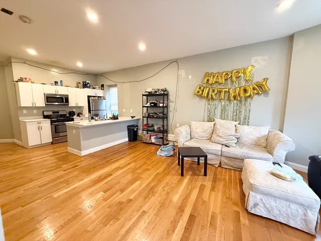 a living room with stainless steel appliances furniture and a wooden floor