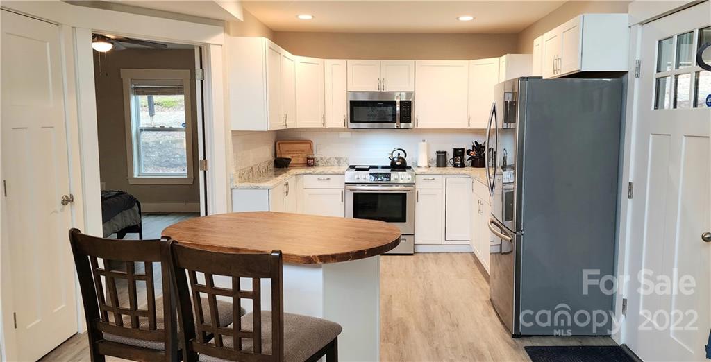 90 Ash Drive Maggie Valley, NC 28751 - Photo 2 of 27 a kitchen with stainless steel appliances granite countertop a refrigerator a stove top oven a sink dishwasher and white cabinets with wooden floor