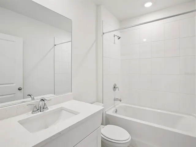 a bathroom with a bathtub shower sink vanity and toilet