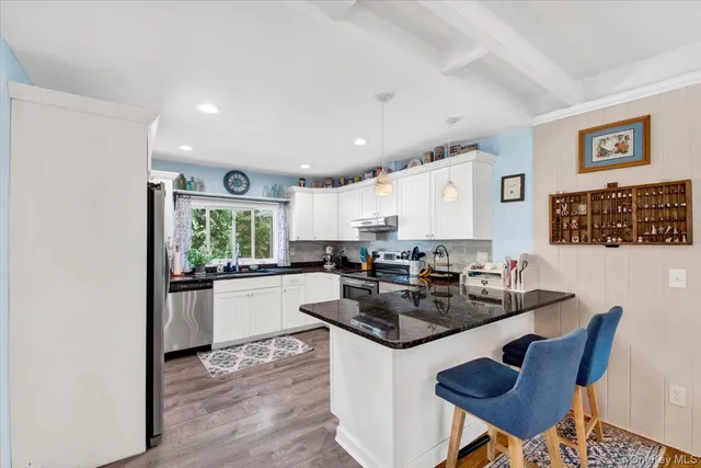 a kitchen with a dining table chairs stove and white cabinets