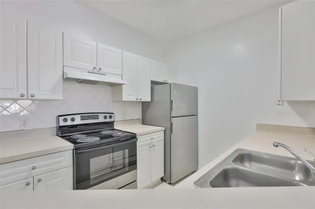 a kitchen with white cabinets and stainless steel appliances