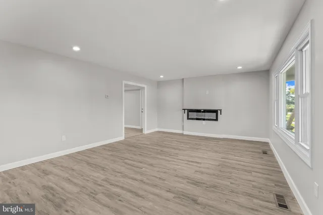 a view of empty room with wooden floor and windows