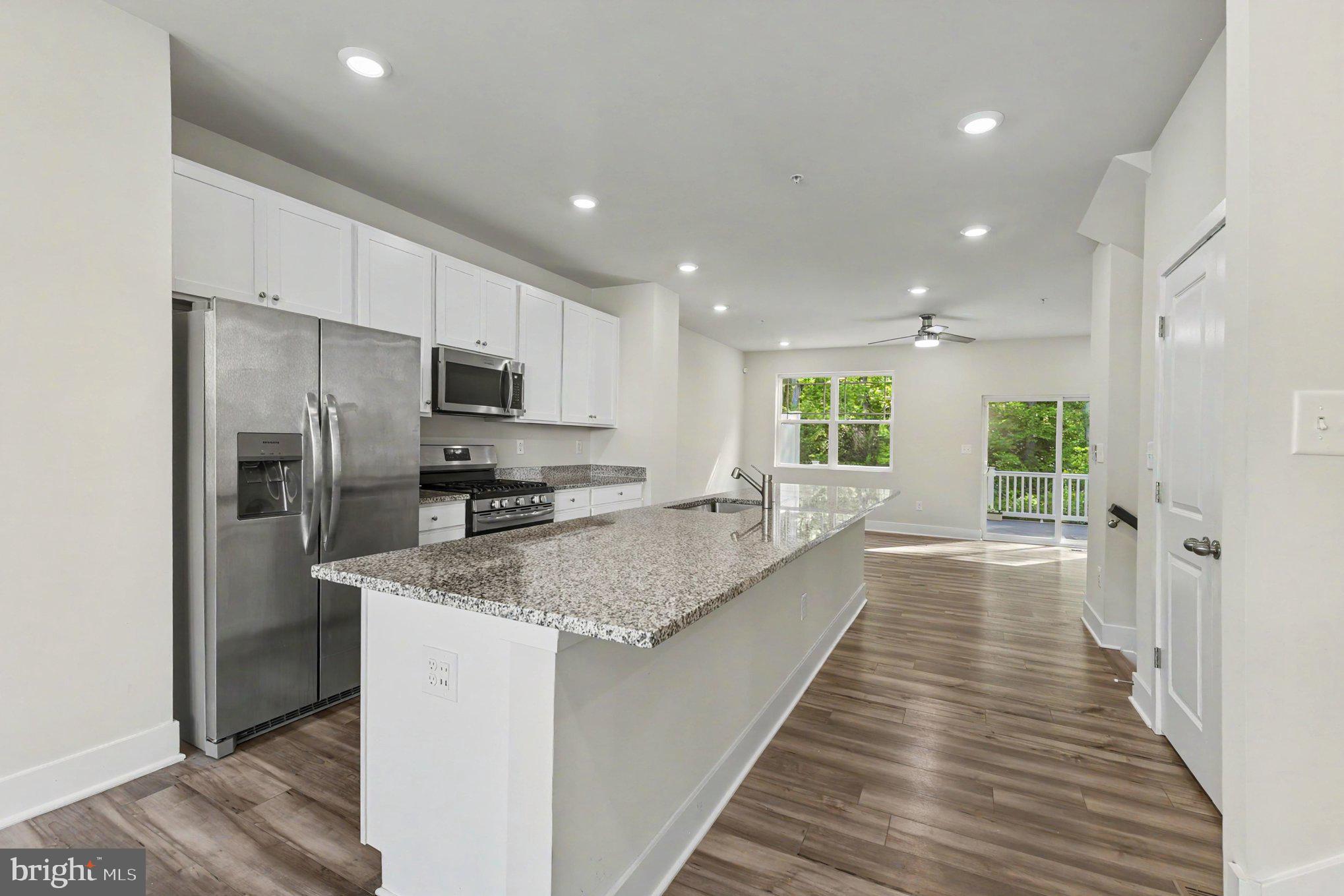 238 Waterstone Road Essex, MD 21221 - Photo 14 of 39 a large kitchen with a center island wooden floor stainless steel appliances and windows