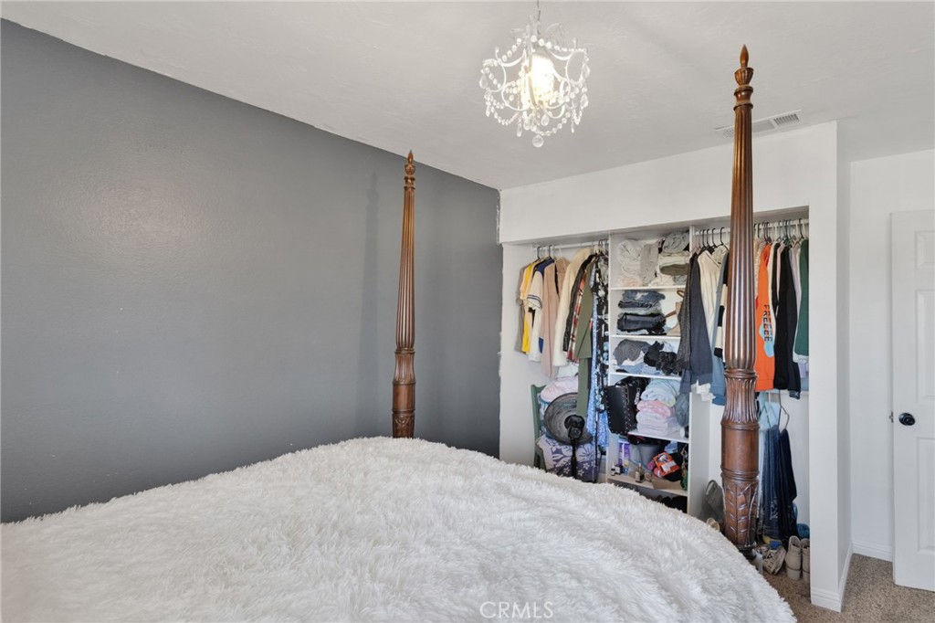 20357 Ituma Road Apple Valley, CA 92308 - Photo 18 of 38 a bedroom with a bed and a chandelier
