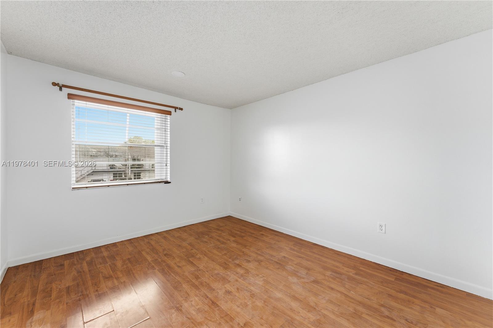 6921 Southwest 129th Avenue, Unit 5 Miami, FL 33183 - Photo 14 of 34 a view of an empty room with wooden floor and a window