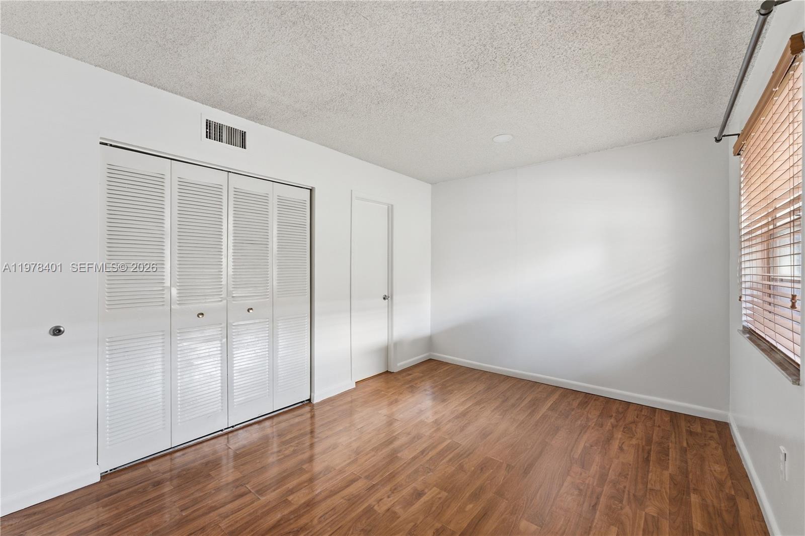 6921 Southwest 129th Avenue, Unit 5 Miami, FL 33183 - Photo 32 of 34 a view of an empty room with wooden floor and a window
