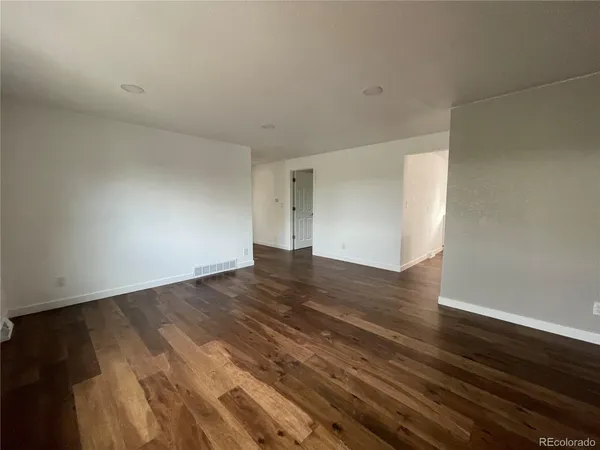 a view of empty room with wooden floor