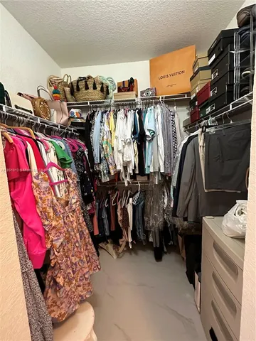 a view of walk in closet with clothes and shoes