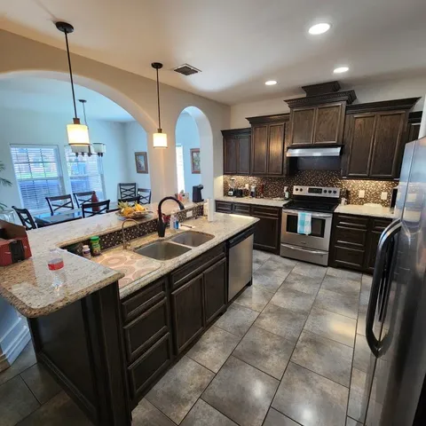 a kitchen with stainless steel appliances granite countertop a sink a stove and a refrigerator