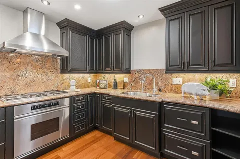 a kitchen with granite countertop stainless steel appliances a stove sink and cabinets