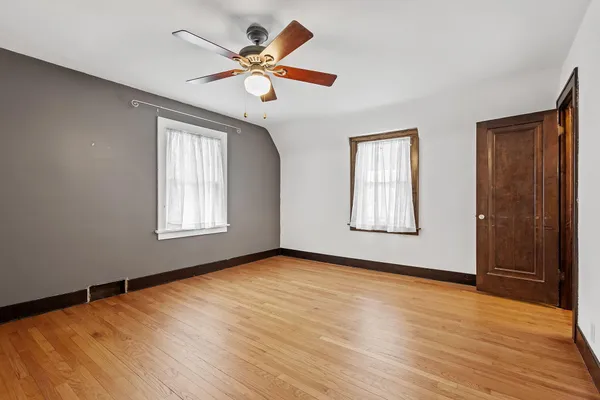 a view of an empty room with window and wooden floor