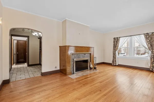 an empty room with wooden floor fireplace and windows