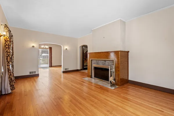 a view of an empty room with wooden floor fireplace and a window