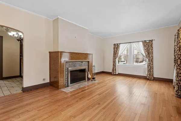 an empty room with wooden floor fireplace and windows