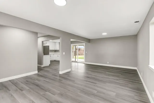 a view of empty room with wooden floor and window