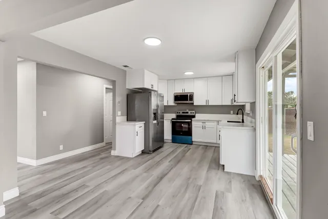 a kitchen with refrigerator a microwave and white cabinets