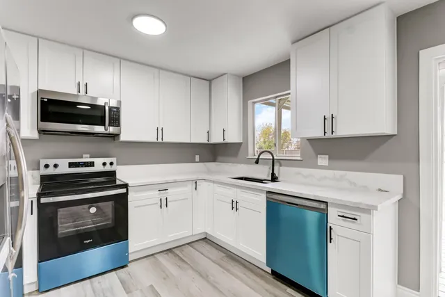 a kitchen with cabinets appliances a sink and a window