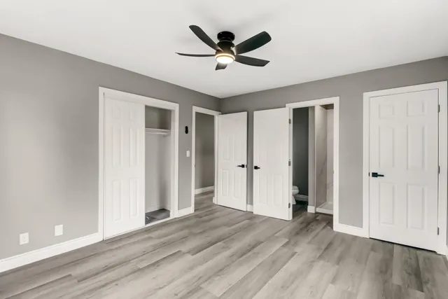 a view of empty room with wooden floor and ceiling fan