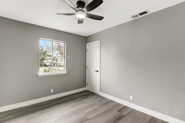 an empty room with windows and fan