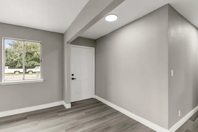 an empty room with wooden floor and windows