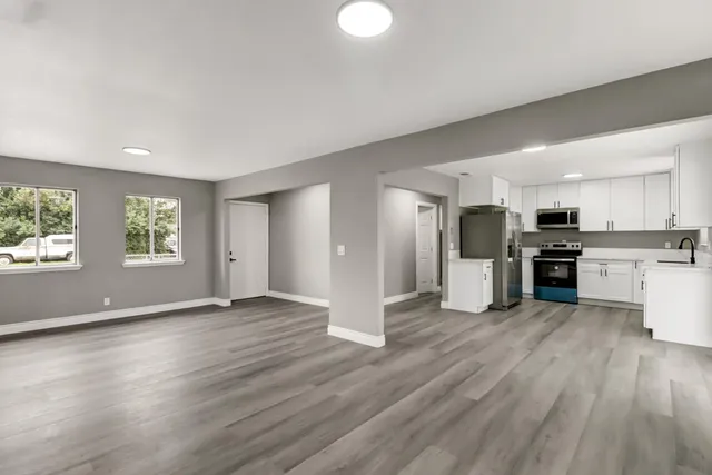 a view of kitchen with stainless steel appliances kitchen island hardwood floor and large window