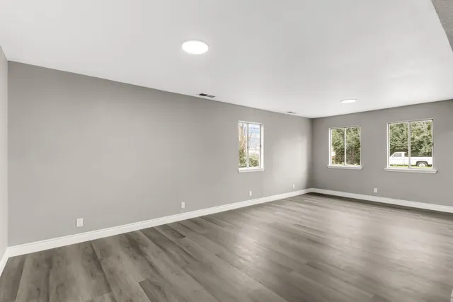 an empty room with wooden floor and windows