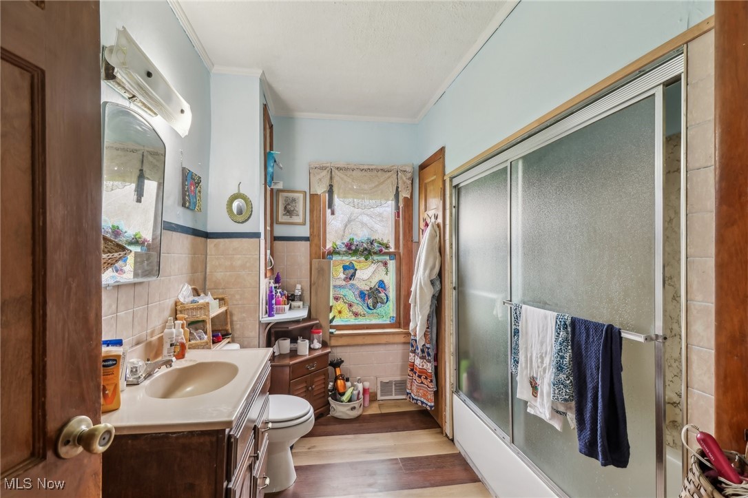 944 Bey Road Akron, OH 44312 - Photo 24 of 47 Full bathroom featuring wood finished floors, tile walls, toilet, ornamental molding, and visible vents