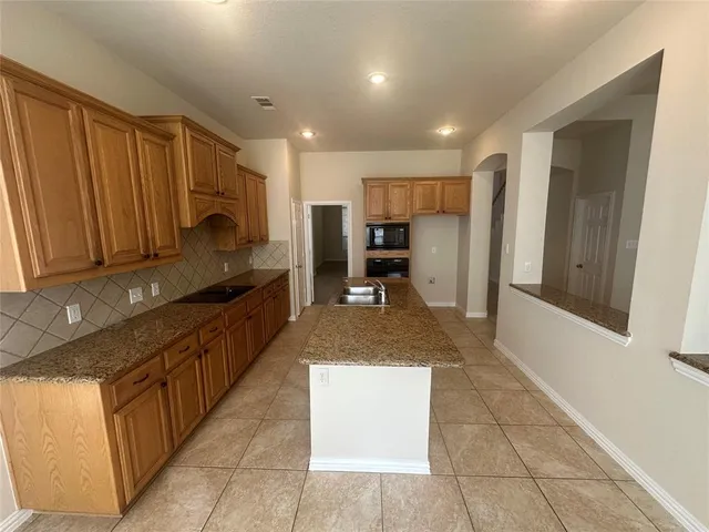 a large kitchen with a large counter top stainless steel appliances and cabinets